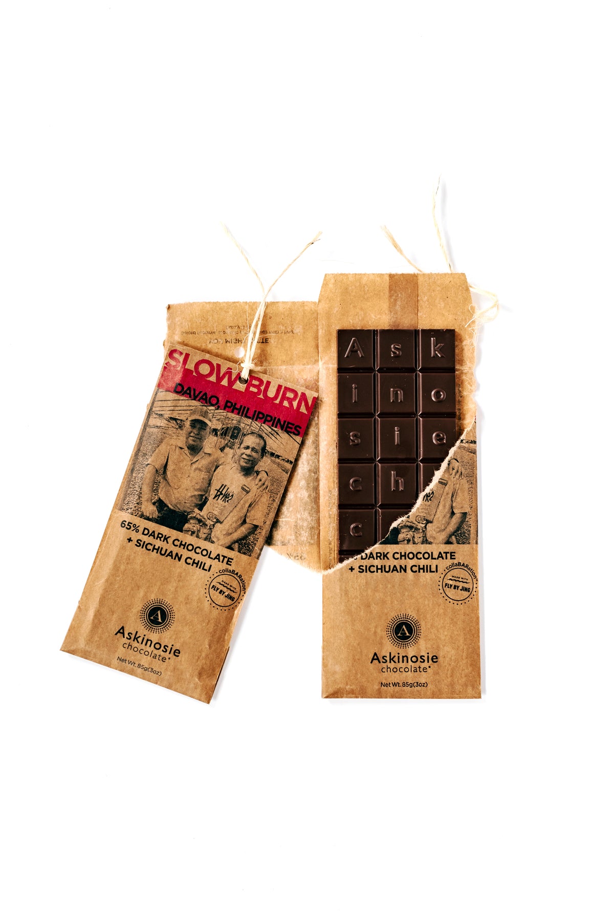 Slightly opened kraft packaging with "Slow Burn" printed in red lettering and Davao, Philippines farmers featured on the front of the wrapper and a brown chocolate bar peeking out of the ripped packaging.