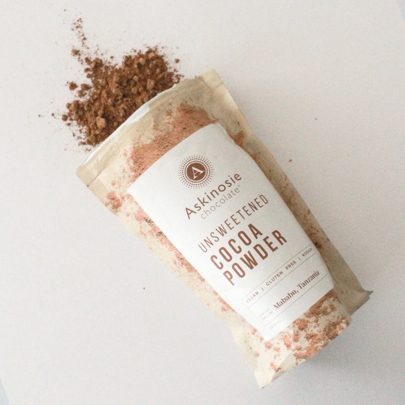 Kraft pouch filled with cocoa powder spilled out on a white background