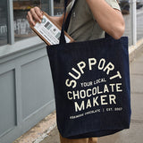Denim tote back screen printed with "Support Your Local Chocolate Maker" in off white ink
