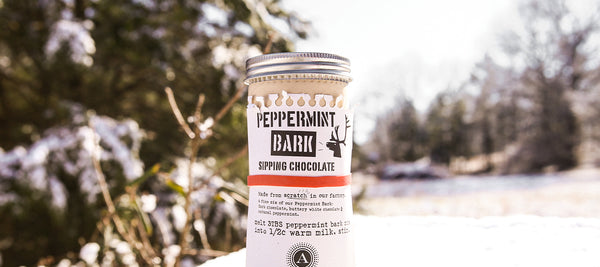Tin of Peppermint Bark Sipping Chocolate sitting in a snow drift