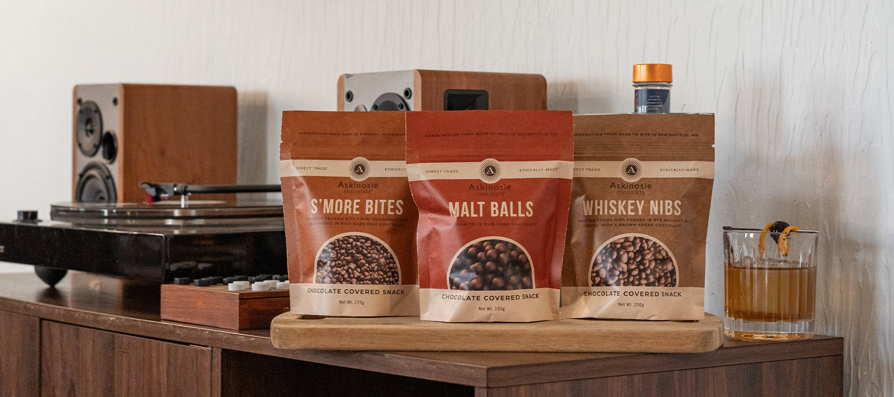Kraft pouches packaged with chocolate covered snacks sit on a wooden credenza 