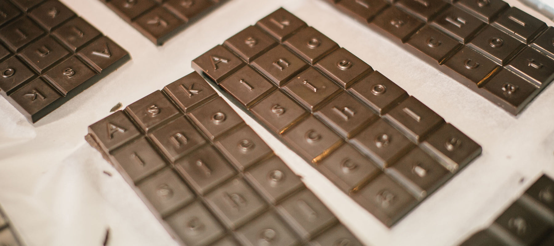 A tray of unpackaged chocolate bars lay on a white paper liner