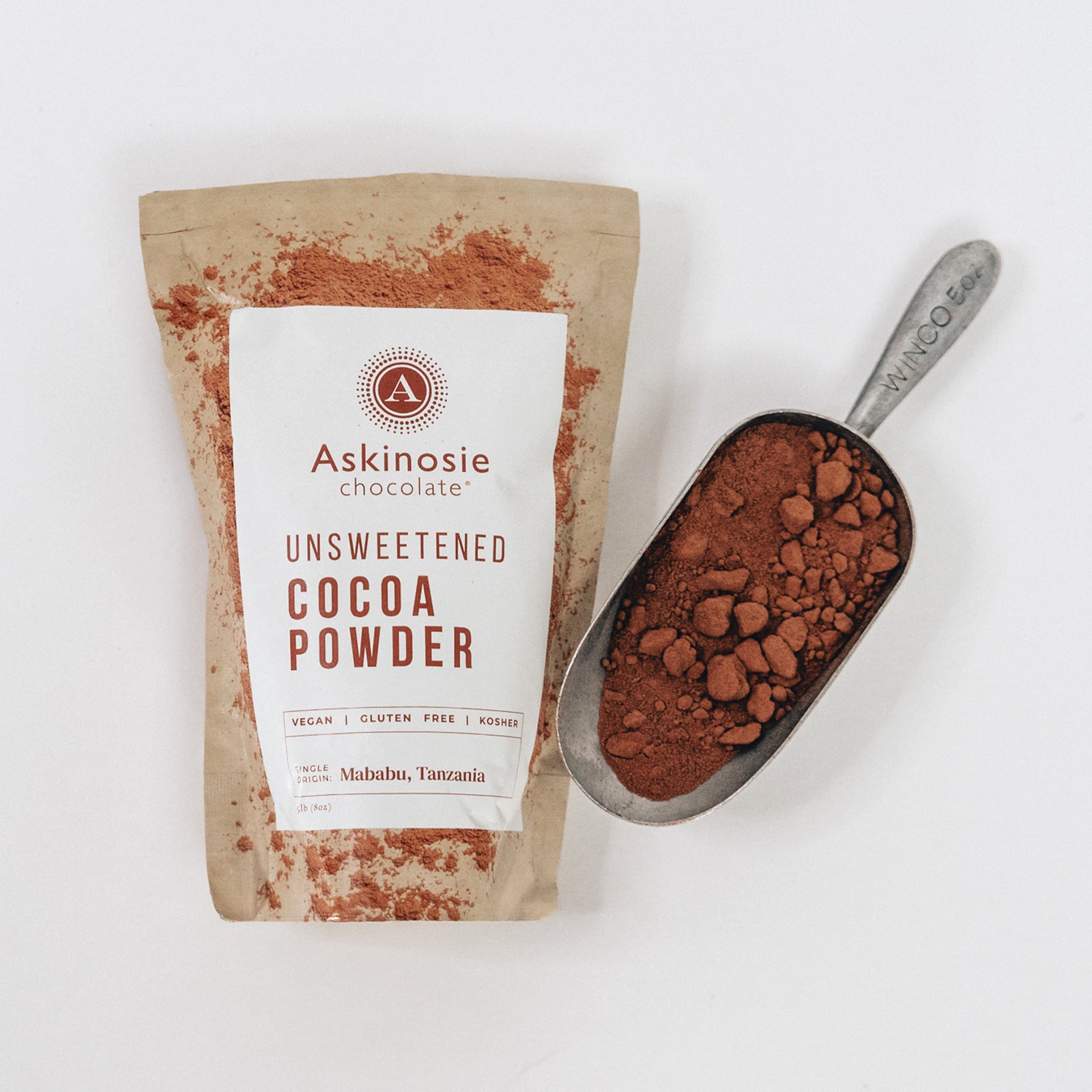 Askinosie unsweetened cocoa powder package with a scoop of cocoa powder on a white background