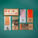 A variety of chocolate bars neatly organized around our festive Holiday Chocolate Tasting Kit kraft brown gift box